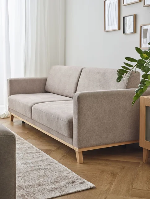 Minimalistyczny salon z beżową sofą na drewnianych nogach